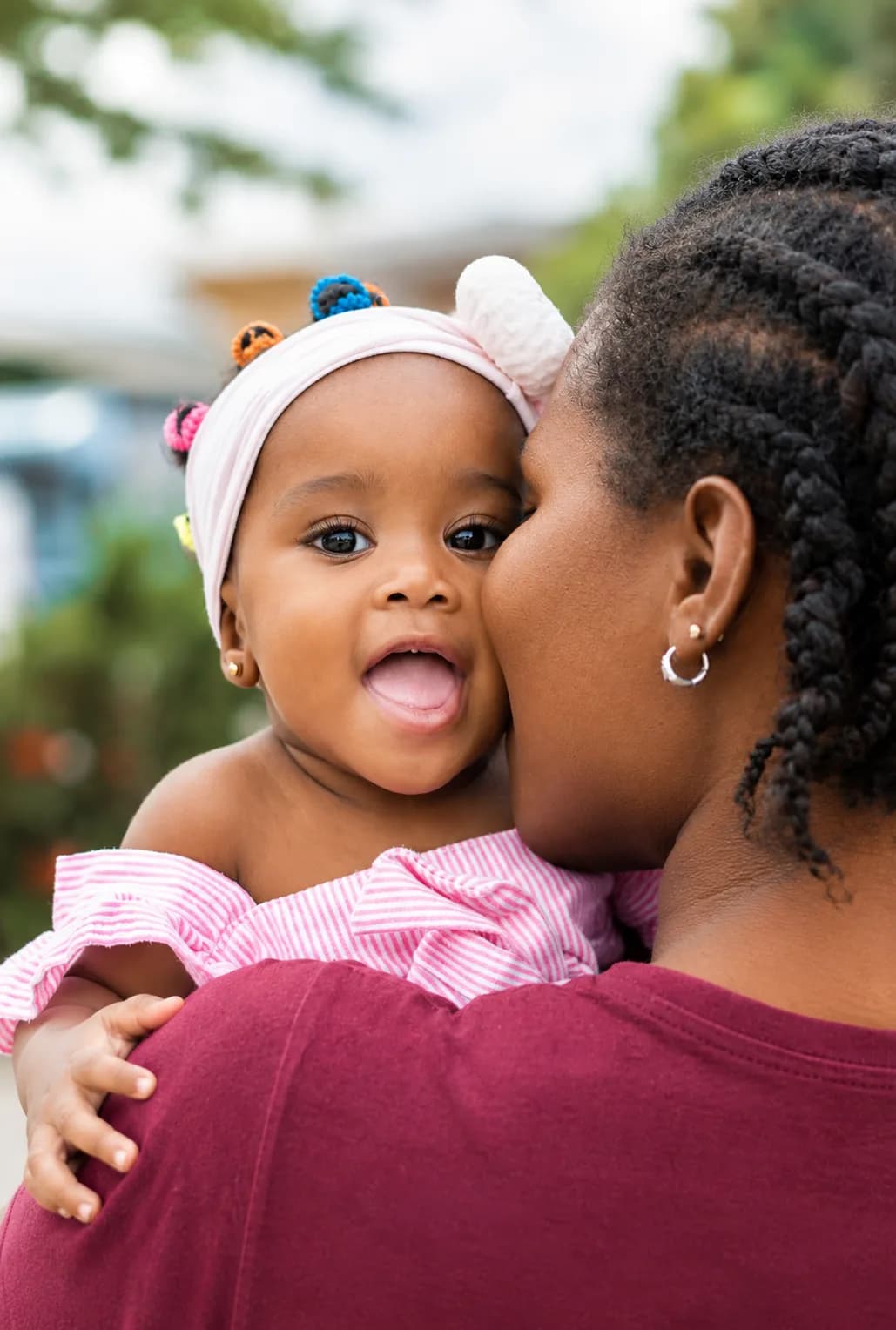 A mother kissing the cheek of her joyful baby girl